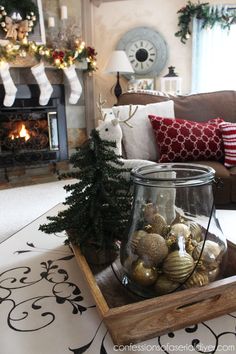 a living room decorated for christmas with ornaments in a glass jar on the coffee table