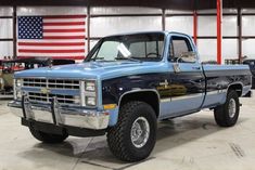 a blue truck parked in a garage next to an american flag