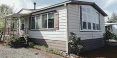 a mobile home is parked in front of some trees and bushes on a sunny day