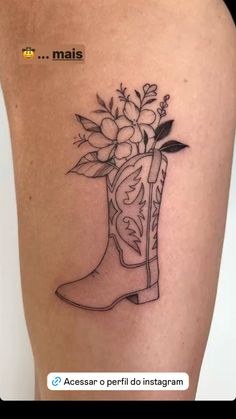 a woman's thigh with a boot and flowers tattoo on her leg, in black and white