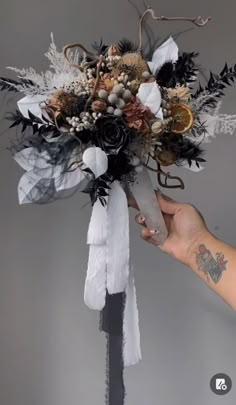 a person holding a bouquet with feathers and flowers