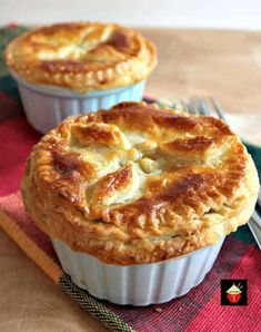 two pies sitting on top of a table next to a fork