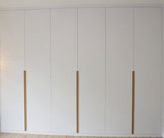 an empty room with white cupboards and wood flooring on the side, in front of a window