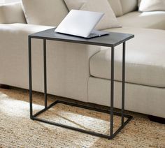 a laptop computer sitting on top of a black table next to a couch in a living room