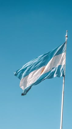 an argentina flag flying in the wind on a clear day with blue sky behind it