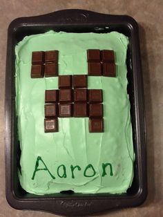 a cake with chocolate squares on it and the word aaron spelled in green frosting