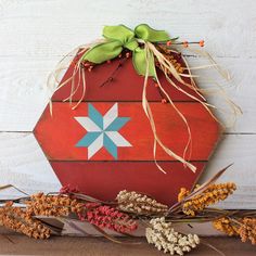 a red potted plant sitting on top of a wooden table next to dried flowers