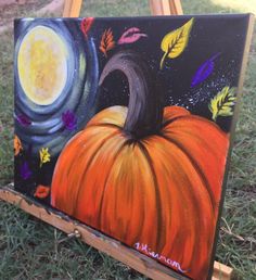 an easel with a painting of a pumpkin on it