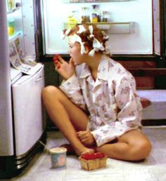 a woman sitting on the floor in front of an open refrigerator