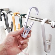 a person holding an umbrella shaped object in front of a rack with hooks on it