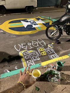 a person is writing on the ground with chalk while holding a beer in their hand