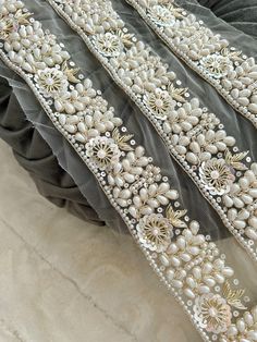 a close up view of the beaded edge of a dress with pearls on it