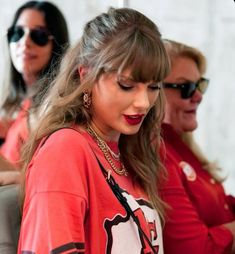 two women in red shirts are looking at their cell phones