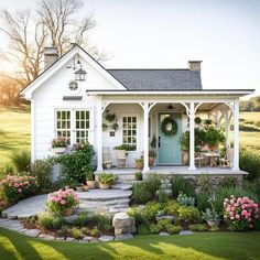 a small white house with flowers in the front yard and steps leading up to it