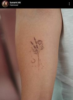 a small flower and moon tattoo on the arm