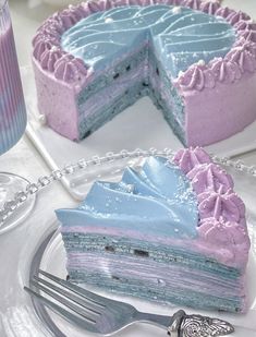 a blue and pink cake sitting on top of a white plate next to a fork