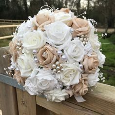 a bridal bouquet with pearls and flowers on a wooden rail in front of a fence