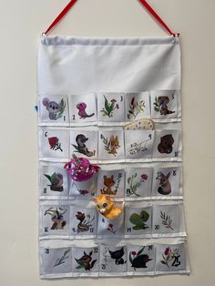 a white wall hanging with pictures of animals and flowers on it's front side