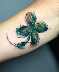 a shamrock tattoo on the arm with green and black ink in it's center