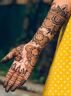 a woman's hand with henna tattoos on her left arm and the top half of