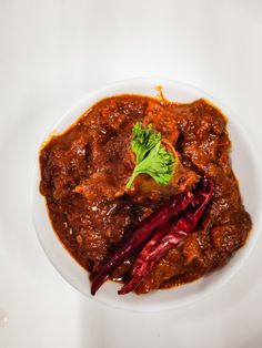 a white plate topped with meat covered in sauce and garnish