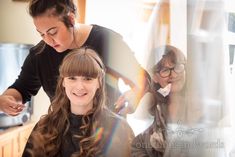 two women are in the kitchen and one is brushing her hair while the other looks on