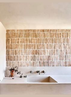 two sinks in front of a wall made out of bamboo sticks and other items on the counter