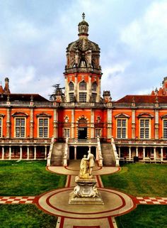 an orange and white building with a fountain in front of it on a grassy lawn