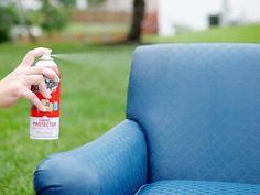 a person holding a spray bottle in front of a blue chair on the grass outside