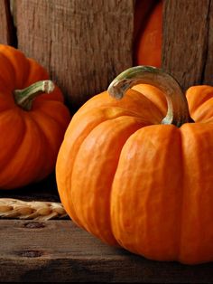 two orange pumpkins sitting on top of a wooden table