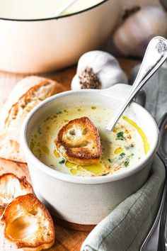 a bowl of soup with bread and garlic on the side