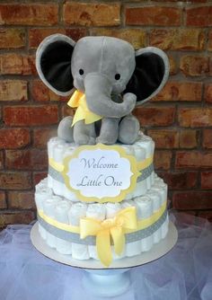 a baby elephant is sitting on top of a diaper cake with yellow ribbon around it