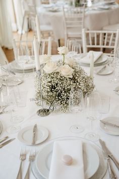 the table is set with white flowers and silverware for an elegant wedding reception or special event