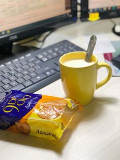 a cup of coffee next to a bag of chips and a computer keyboard on a desk