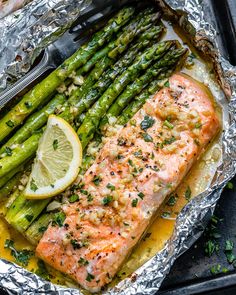 salmon and asparagus in foil with lemon wedges on the side for garnish