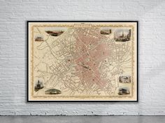 an old map is hanging on the wall in front of a white brick wall with a black frame