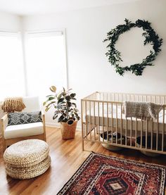 a baby crib in a white room next to a rug and potted plant