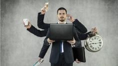 a man in a suit holding a laptop and two clocks