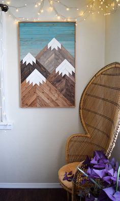 a chair sitting in front of a painting on the wall next to a basket filled with purple flowers