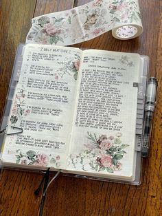 an open bible on a wooden table next to a roll of tape