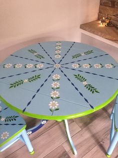 a blue table with flowers painted on it and two chairs next to the fire place