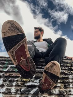 a man sitting on top of a roof with his feet propped up in the air