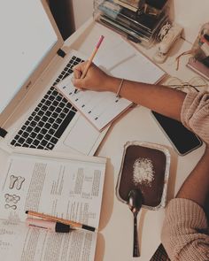 a person sitting at a desk with a laptop, notebook and pen in front of them