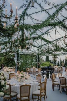 an outdoor dining area with chandeliers and tables set for formal function at dusk