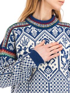 a woman wearing a blue and white sweater with an intricate pattern on it's sleeves