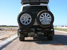 the back end of a white jeep with two tires on it's flatbed