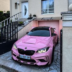 a pink sports car parked in front of a house with stairs and steps leading up to it