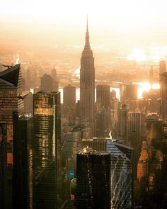 an aerial view of a city with skyscrapers and buildings in the foreground at sunset