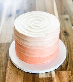 a white and pink cake sitting on top of a wooden table