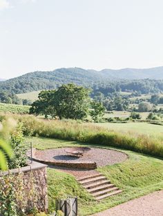 an outdoor fire pit in the middle of a grassy area with steps leading up to it